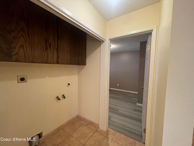 laundry area featuring electric dryer hookup, cabinets, hookup for a gas dryer, light wood-type flooring, and a textured ceiling