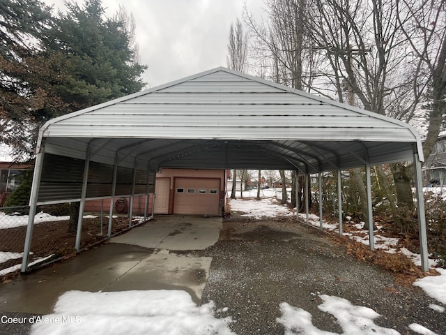 snow covered parking with a carport and a garage