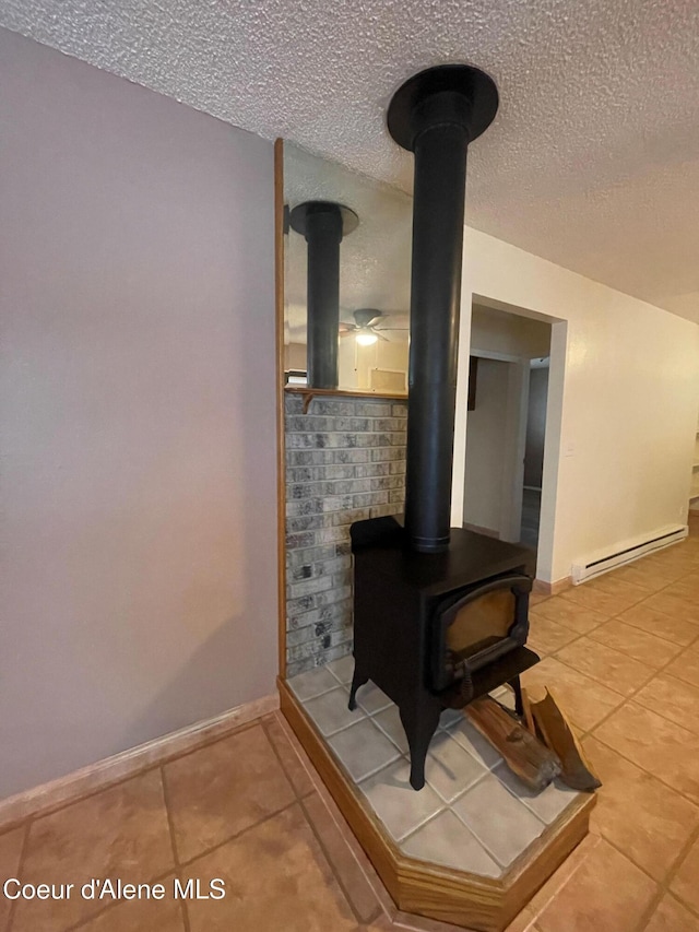 details with a textured ceiling, a wood stove, and a baseboard heating unit