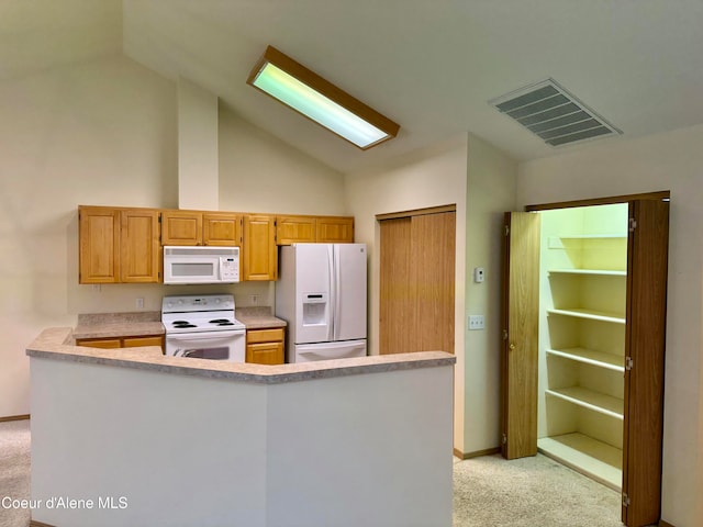 kitchen with lofted ceiling, light colored carpet, white appliances, and kitchen peninsula