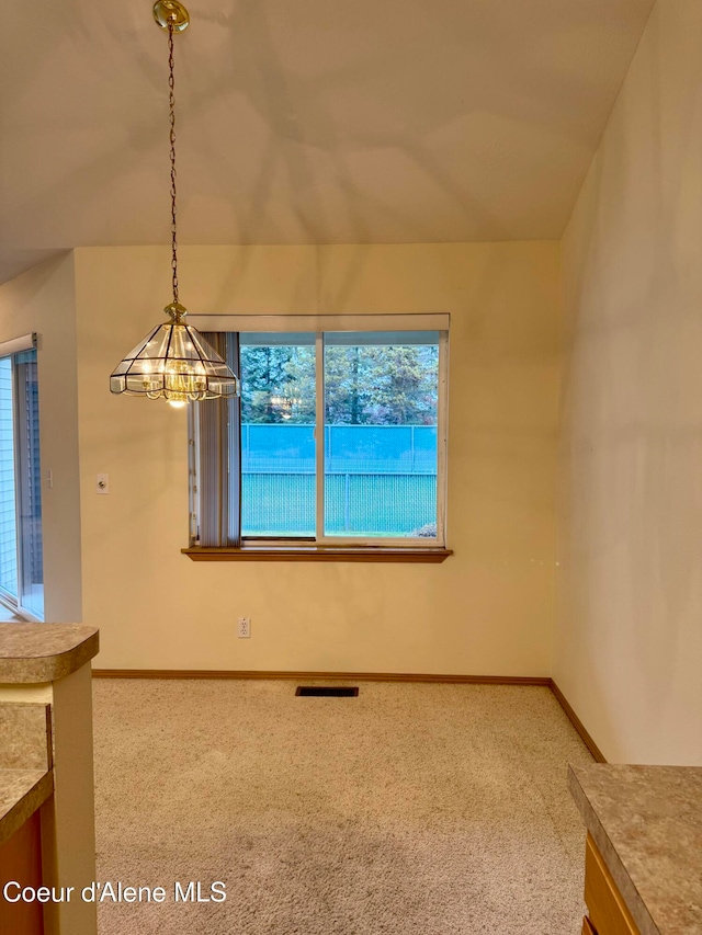 carpeted empty room with a chandelier