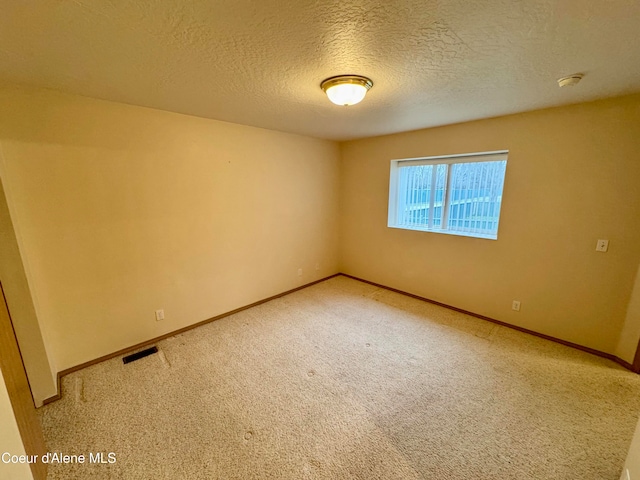 carpeted empty room featuring a textured ceiling