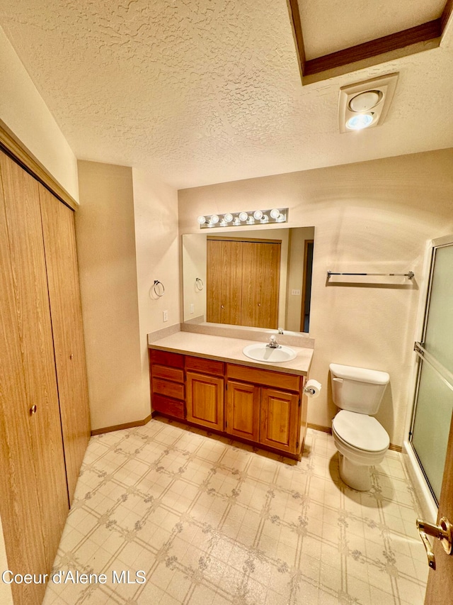 bathroom featuring vanity, an enclosed shower, a textured ceiling, and toilet