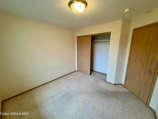 unfurnished bedroom featuring light colored carpet, a textured ceiling, and a closet