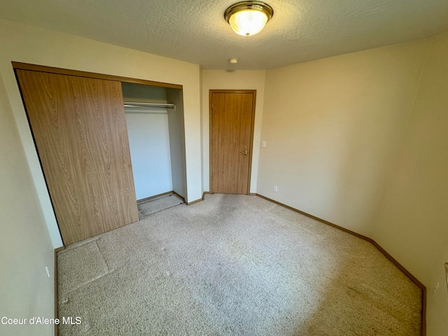 unfurnished bedroom with light colored carpet, a textured ceiling, and a closet