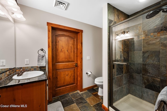 bathroom featuring vanity, toilet, and a shower with door