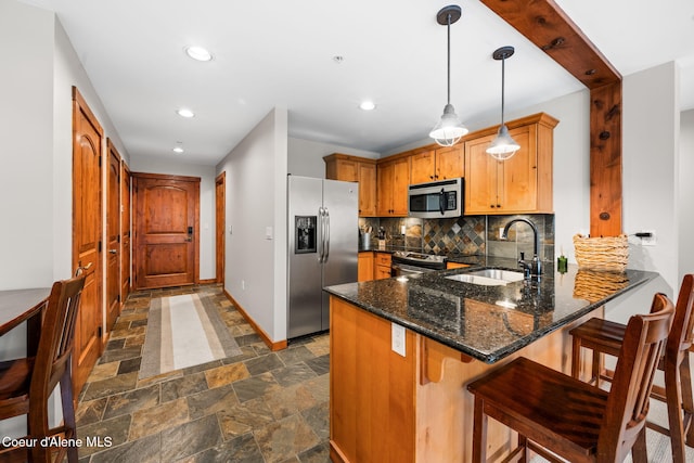 kitchen featuring sink, decorative backsplash, appliances with stainless steel finishes, decorative light fixtures, and kitchen peninsula