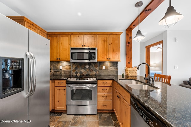 kitchen with backsplash, sink, hanging light fixtures, dark stone countertops, and stainless steel appliances