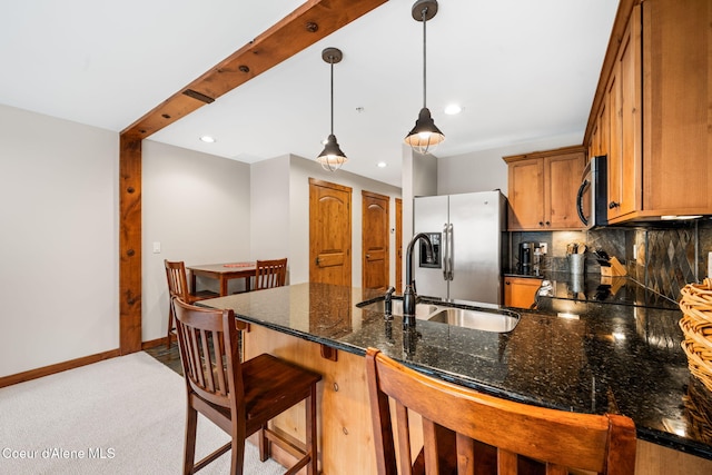 kitchen featuring sink, backsplash, dark stone counters, pendant lighting, and appliances with stainless steel finishes