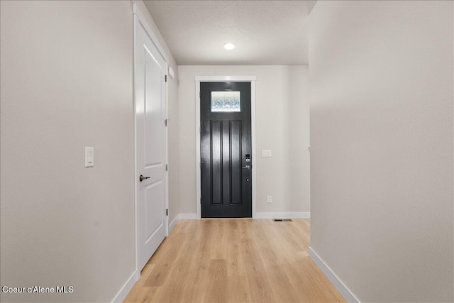 doorway to outside with a textured ceiling and light hardwood / wood-style floors