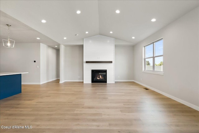 unfurnished living room with a large fireplace, light wood-type flooring, and vaulted ceiling