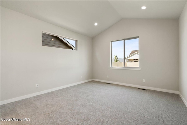 carpeted empty room featuring vaulted ceiling