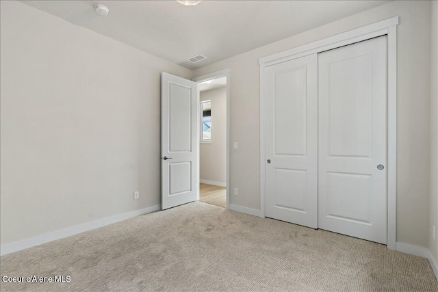 unfurnished bedroom featuring a closet and light colored carpet