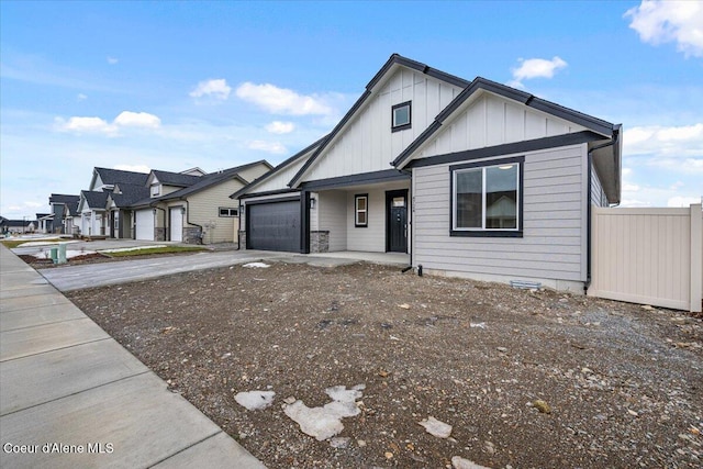 view of front of property featuring an attached garage, board and batten siding, fence, a residential view, and driveway