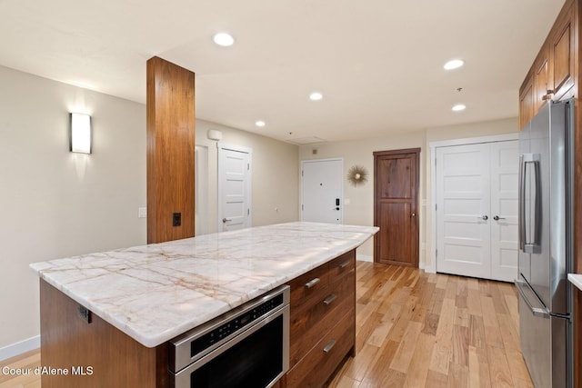 kitchen with stainless steel fridge, a kitchen island, and light hardwood / wood-style flooring