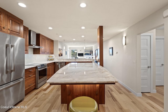 kitchen featuring wall chimney range hood, a kitchen island, a kitchen bar, kitchen peninsula, and stainless steel appliances