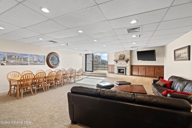 living room featuring a fireplace, carpet flooring, and a drop ceiling