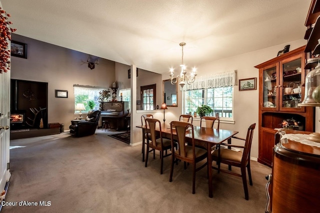 carpeted dining room with plenty of natural light, a textured ceiling, and an inviting chandelier