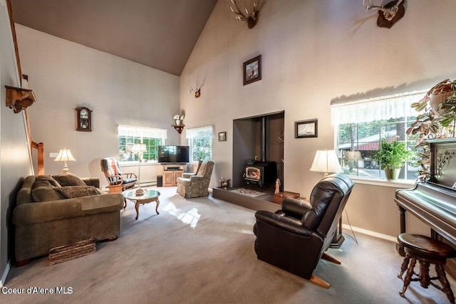 living room with a wood stove, plenty of natural light, carpet floors, and high vaulted ceiling