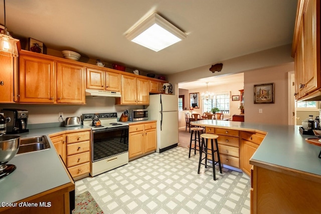 kitchen featuring a breakfast bar, white appliances, hanging light fixtures, and a chandelier