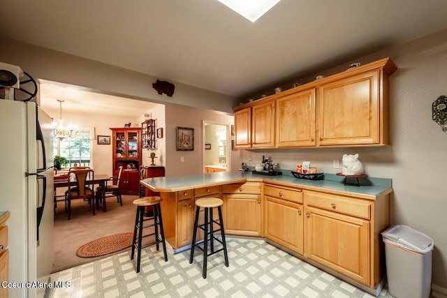 kitchen with a kitchen breakfast bar, decorative light fixtures, a notable chandelier, white fridge, and kitchen peninsula