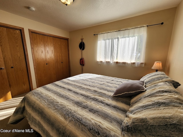 bedroom featuring a textured ceiling and two closets