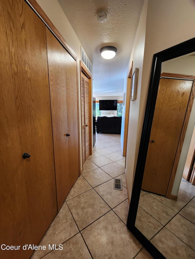 corridor with light tile patterned flooring and a textured ceiling