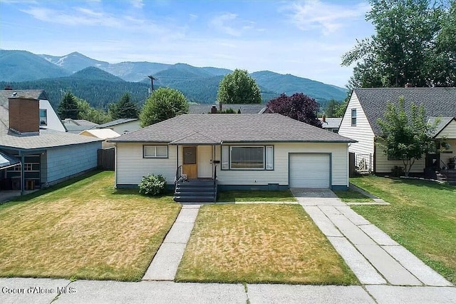 single story home featuring a mountain view, a front lawn, and a garage