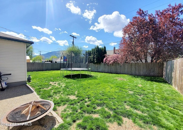 view of yard with a trampoline and an outdoor fire pit