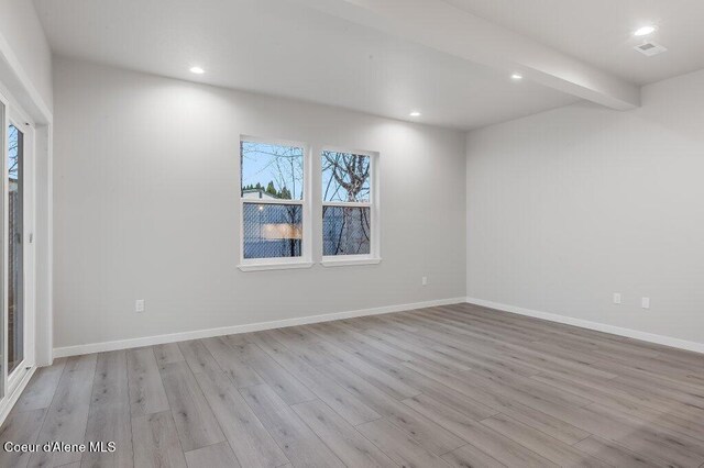 unfurnished room with light hardwood / wood-style floors and beam ceiling