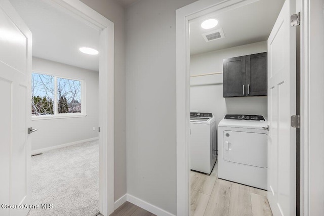 washroom featuring washer and clothes dryer, cabinets, and light hardwood / wood-style flooring