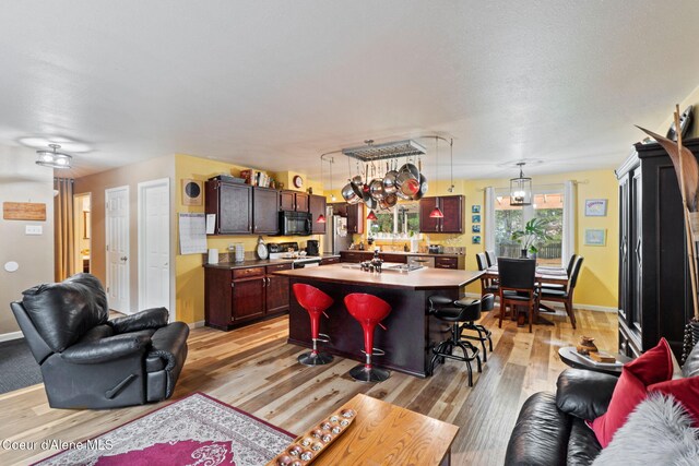 11673 N Boyer Rd, Sandpoint, ID 83864 - kitchen with range with electric stovetop, black microwave, open floor plan, light wood-style flooring, and a kitchen breakfast bar