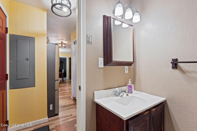 11673 N Boyer Rd, Sandpoint, ID 83864 - bathroom featuring electric panel, wood finished floors, vanity, a textured wall, and baseboards