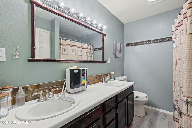11673 N Boyer Rd, Sandpoint, ID 83864 - bathroom featuring wood finished floors, toilet, double vanity, baseboards, and a shower with curtain