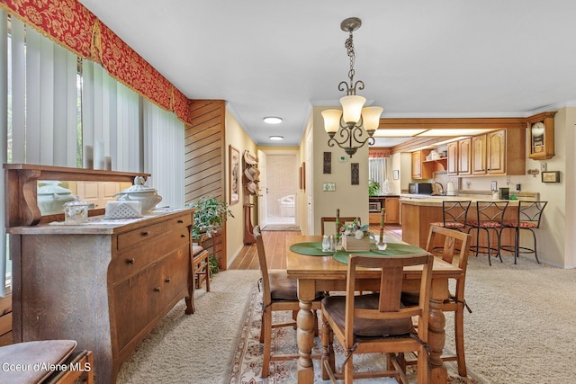 dining area with light carpet, crown molding, and a notable chandelier