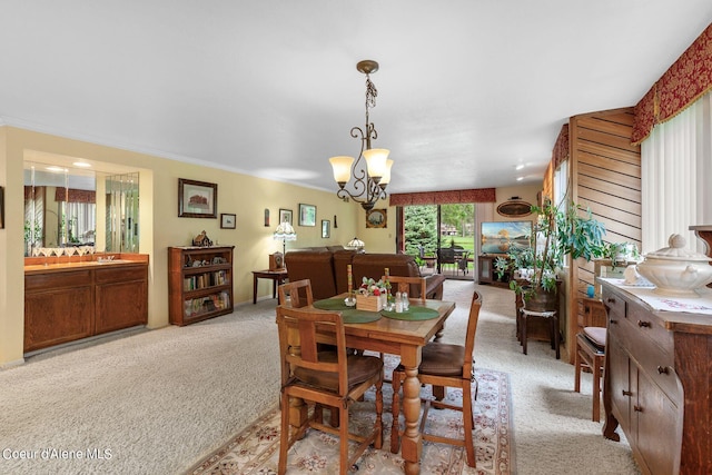 carpeted dining room featuring a chandelier and ornamental molding