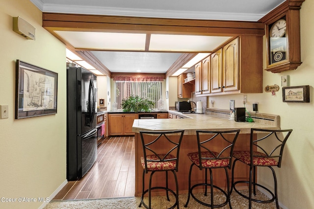 5299 W Green Ct # 5, Rathdrum, ID 83858 - kitchen featuring a peninsula, freestanding refrigerator, a kitchen breakfast bar, wood finished floors, and brown cabinetry