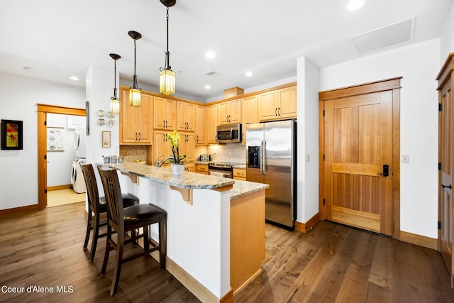 kitchen featuring hanging light fixtures, light stone counters, dark hardwood / wood-style floors, kitchen peninsula, and appliances with stainless steel finishes