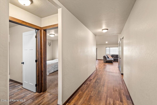 hall featuring a textured ceiling and dark wood-type flooring