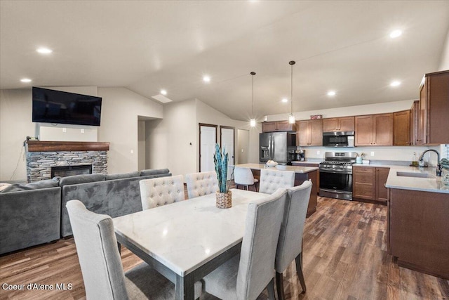 dining area with a fireplace, dark hardwood / wood-style flooring, vaulted ceiling, and sink