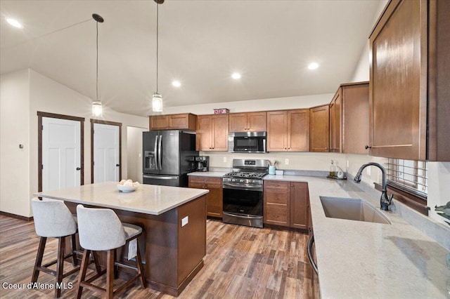 kitchen featuring stainless steel appliances, sink, wood-type flooring, hanging light fixtures, and lofted ceiling