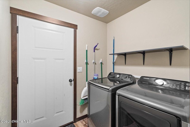 laundry area with a textured ceiling, hardwood / wood-style flooring, and washer and clothes dryer