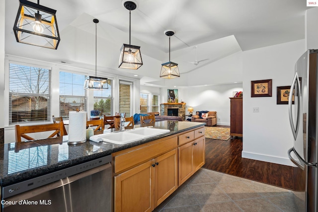 kitchen featuring appliances with stainless steel finishes, dark hardwood / wood-style flooring, sink, pendant lighting, and a stone fireplace