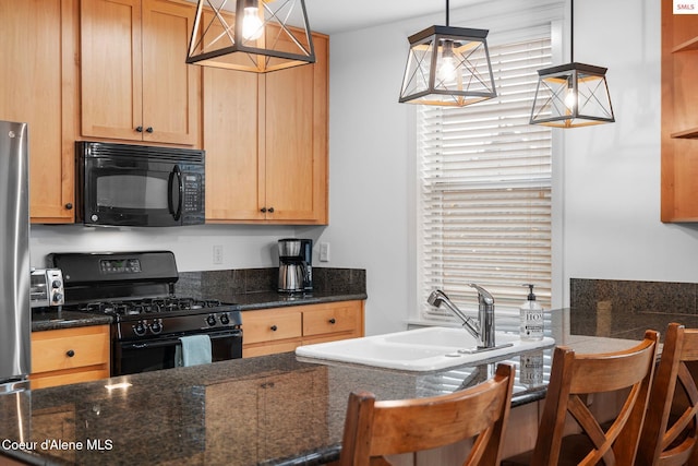 kitchen featuring black appliances, a kitchen breakfast bar, sink, dark stone countertops, and decorative light fixtures