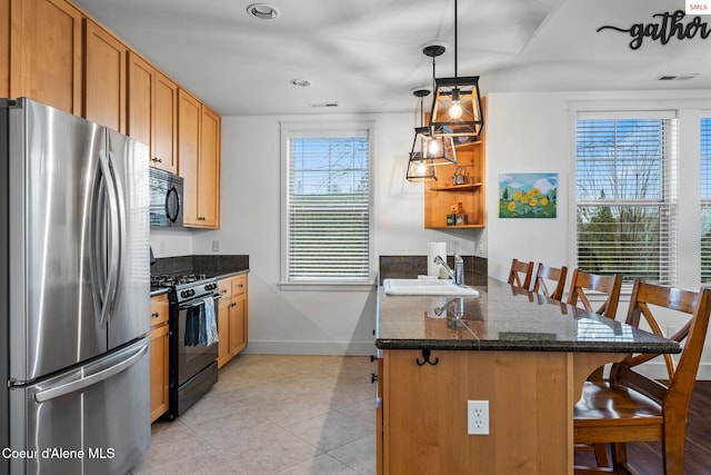 kitchen featuring a breakfast bar area, kitchen peninsula, a wealth of natural light, and black appliances