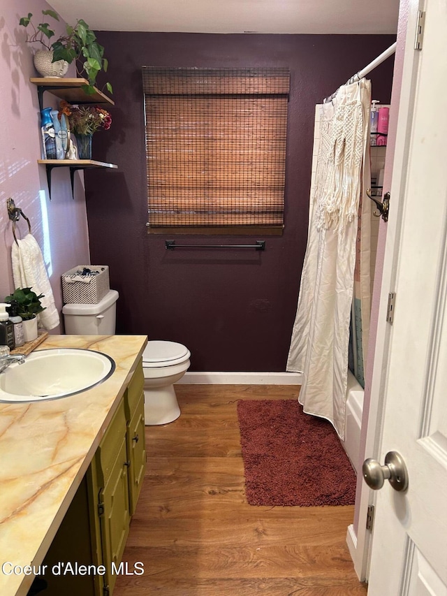 full bathroom featuring hardwood / wood-style floors, vanity, toilet, and shower / tub combo