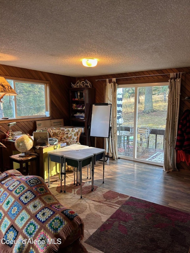 living room featuring hardwood / wood-style floors, a textured ceiling, and wooden walls