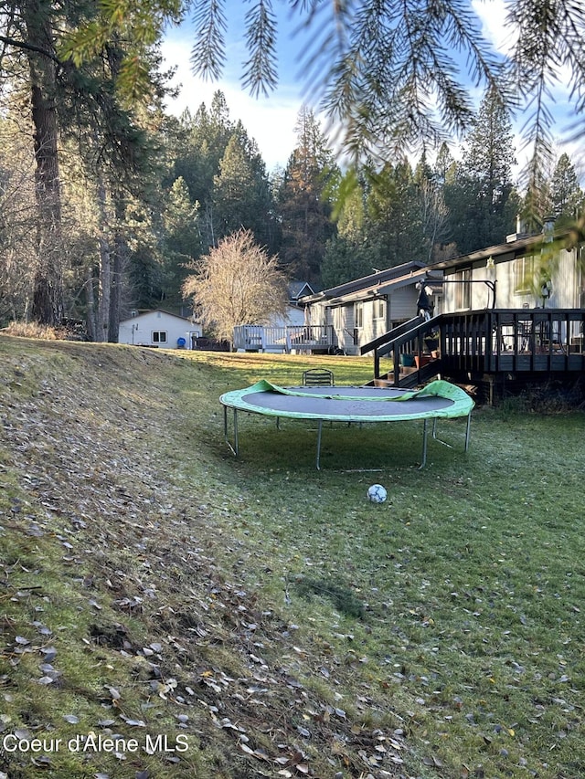 view of yard with a trampoline and a deck