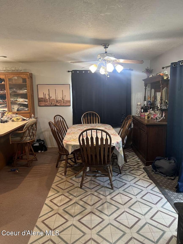 dining room with ceiling fan, a textured ceiling, and light carpet