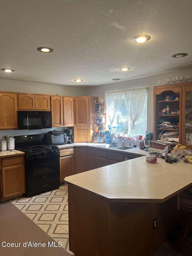 kitchen with kitchen peninsula, sink, black appliances, and a textured ceiling